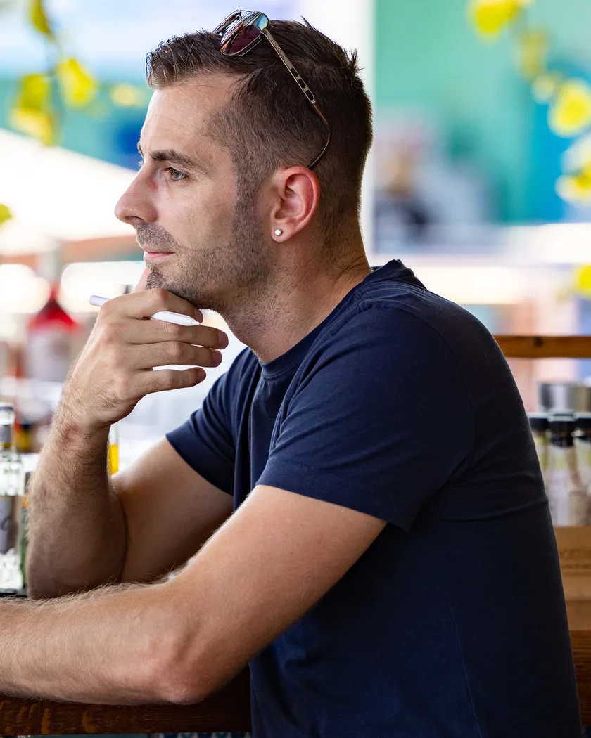 Oliver Albrecht an einer Bar auf Zypern, nachdenklich, die Hand am Kinn